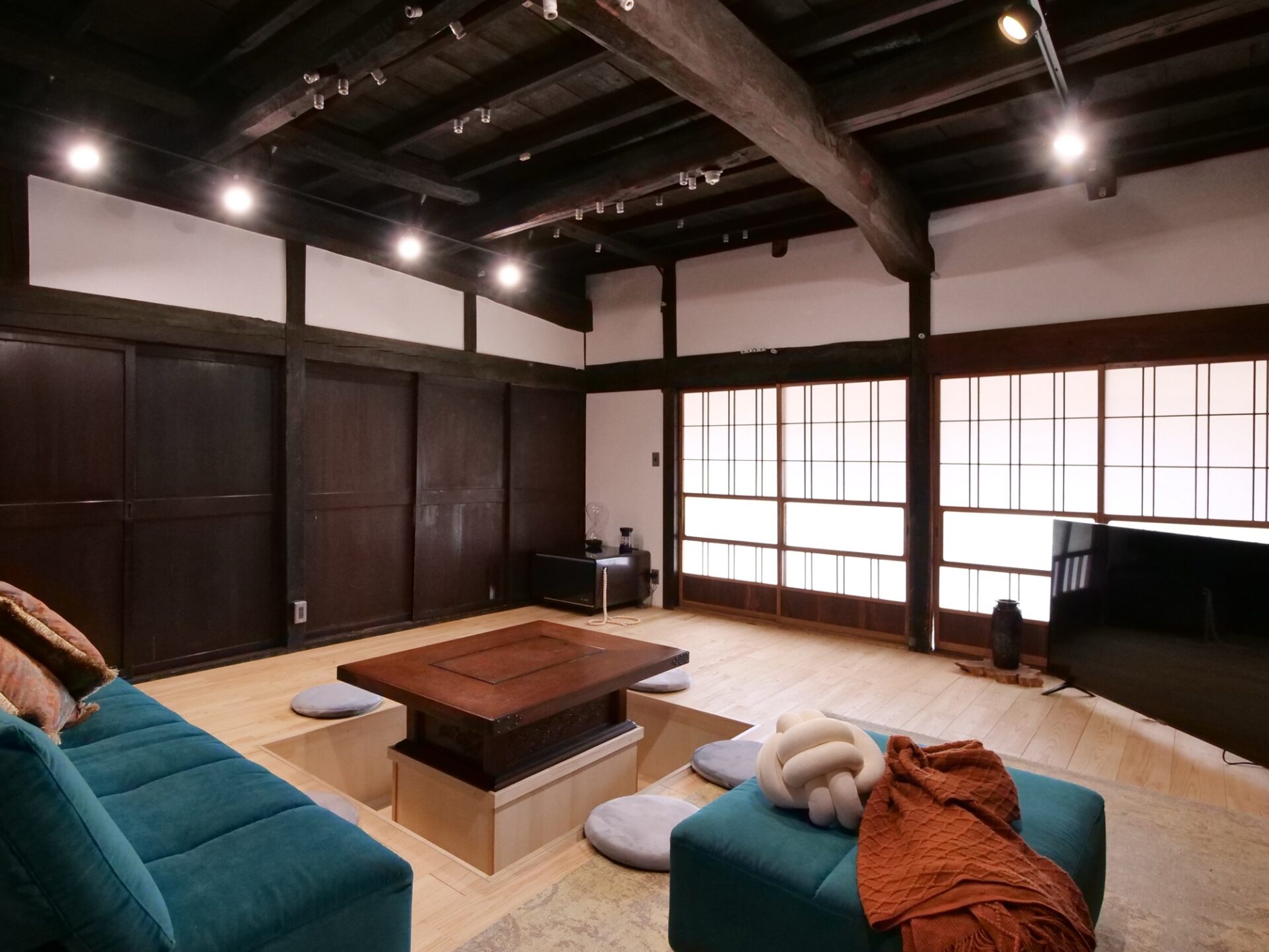 松本市の古民家をリノベーションした和モダンなリビング。天井の梁を活かした開放的な空間に、障子からの柔らかな光が差し込む落ち着いた雰囲気の部屋。